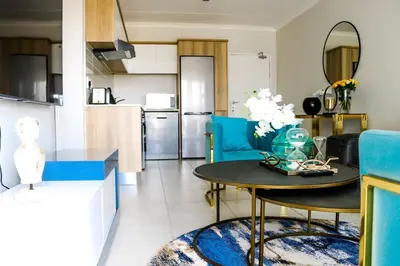 a kitchen and living room with a table and blue chairs at Twelve Eighty at The Blyde Crystal Lagoon in Pretoria