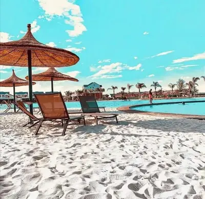 a beach with two chairs and an umbrella and a pool at Twelve Eighty at The Blyde Crystal Lagoon in Pretoria