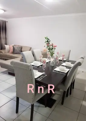 a dining room with a black table and chairs at RnR Crystal Lagoon in Pretoria