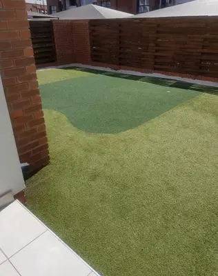 a garden with green grass and a brick wall at RnR Crystal Lagoon in Pretoria