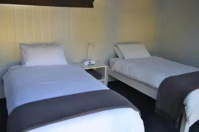 a room with two beds and a table with a lamp at SleepOver Orpen Gate in Acornhoek