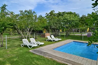 a swimming pool with lounge chairs and a swimming pool at SleepOver Orpen Gate in Acornhoek