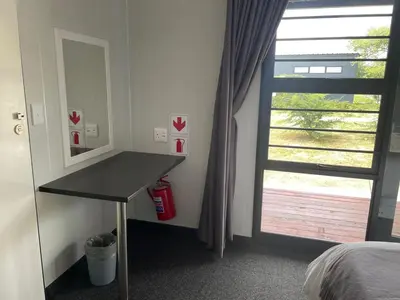 a bedroom with a desk next to a window at SleepOver Orpen Gate in Acornhoek