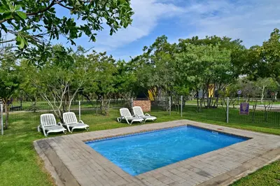 a swimming pool with two lounge chairs and a swimming pool at SleepOver Orpen Gate in Acornhoek
