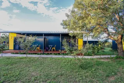 a blue and yellow house with two chairs in front of it at SleepOver Orpen Gate in Acornhoek