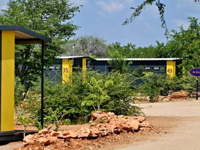 a yellow building with a pile of rocks in front of it at SleepOver Beitbridge in Musina