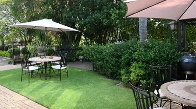 a patio with a table and chairs and an umbrella at LUXURY EN-SUITE KING ROOM @ 4 STAR GUEST HOUSE in Middelburg