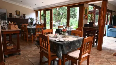 a dining room with tables and chairs and windows at LUXURY EN-SUITE KING ROOM @ 4 STAR GUEST HOUSE in Middelburg