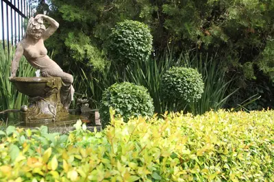 a statue of a woman sitting in a fountain in a garden at LUXURY EN-SUITE KING ROOM @ 4 STAR GUEST HOUSE in Middelburg