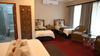a hotel room with two beds and a bathroom at LUXURY FAMILY EN-SUITE ROOM @ 4 STAR GUEST HOUSE in Middelburg