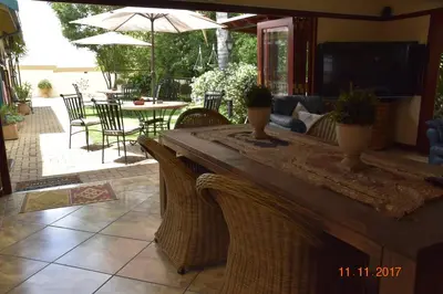 a patio with a table with chairs and an umbrella at LUXURY FAMILY EN-SUITE ROOM @ 4 STAR GUEST HOUSE in Middelburg