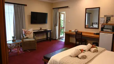 a hotel room with a bed and a desk at LUXURY FAMILY EN-SUITE ROOM @ 4 STAR GUEST HOUSE in Middelburg