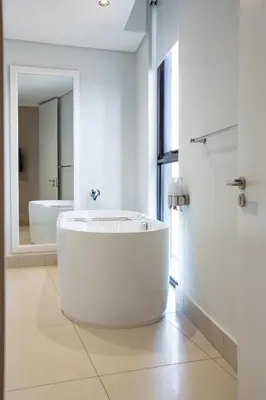 a large white bathroom with a tub and a mirror at Ellipse Waterfall Executive Apartments in Midrand