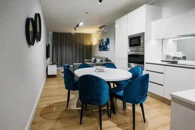 a kitchen and dining room with a table and blue chairs at Ellipse Waterfall Executive Apartments in Midrand