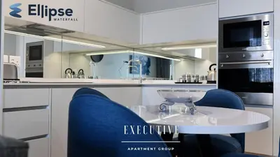 a kitchen with a table and two blue chairs at Ellipse Waterfall Executive Apartments in Midrand