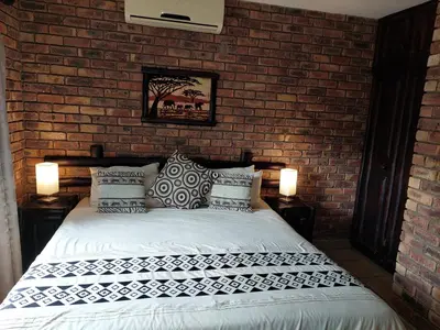 a bedroom with a bed with a brick wall at Khumbula iAfrica 2 in Marloth Park