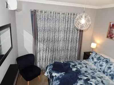 a bedroom with a bed and a chair and a chandelier at Locust Retreat Immaculate 2bedroom cottage in Marloth Park