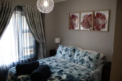 a bedroom with a bed and a chandelier at Locust Retreat Immaculate 2bedroom cottage in Marloth Park