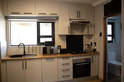 a kitchen with white cabinets and a sink and a window at Locust Retreat Immaculate 2bedroom cottage in Marloth Park