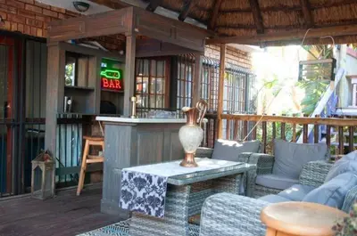 an outdoor patio with couches and a table and a bar at Goldpot Faerie Glen near Sun Bet Arena in Pretoria