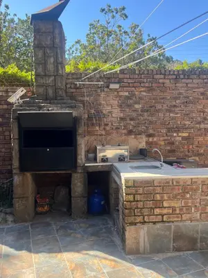 a stone kitchen with a sink and a tv in a brick wall at Goldpot Faerie Glen near Sun Bet Arena in Pretoria