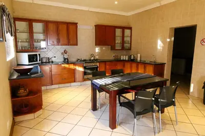 a kitchen with wooden cabinets and a table and chairs at Waterval Self-Catering Holiday Home in Sabie
