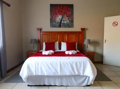 a bedroom with a large bed with red pillows at Waterval Self-Catering Holiday Home in Sabie