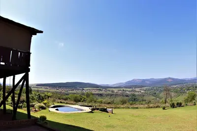 a house with a swimming pool in a grassy field at Waterval Self-Catering Holiday Home in Sabie