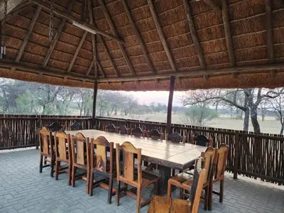 a large wooden table and chairs in a pavilion at Isilwane Bush Camp in Pretoria