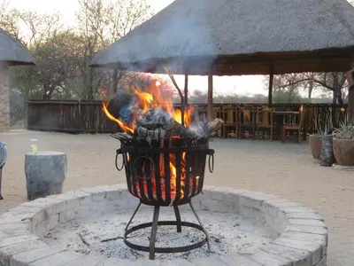 a fire grill in a courtyard with flames at Isilwane Bush Camp in Pretoria