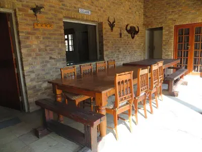 a wooden table and chairs in a room with a brick wall at Isilwane Bush Camp in Pretoria