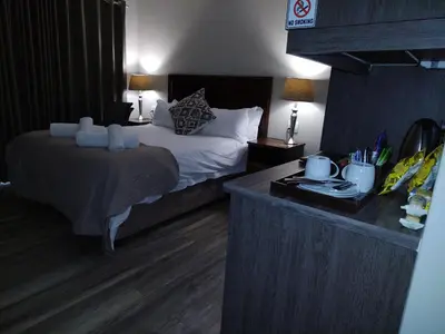 a hotel room with a bed and a desk at Unitas Guesthouse in Centurion