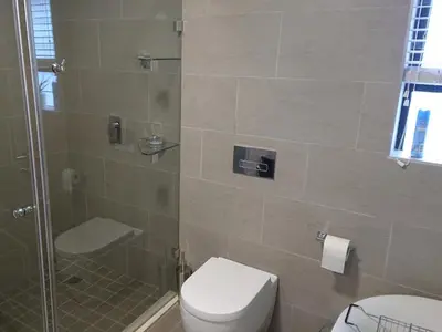 a bathroom with a toilet and a glass shower at Unitas Guesthouse in Centurion