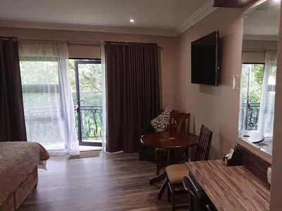 a bedroom with a bed and a table and a dining room at Unitas Guesthouse in Centurion