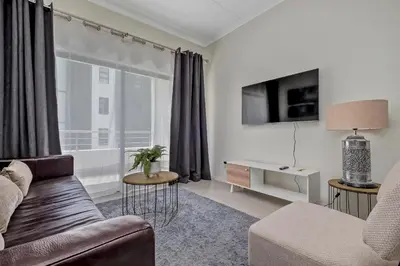 a living room with a couch and a large window at Smart Apartment in Midrand