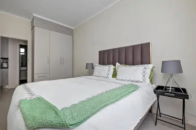 a bedroom with a large white bed with a green blanket at Smart Apartment in Midrand