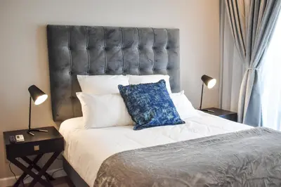 a bedroom with a large bed with a blue pillow on it at Menlyn Apartment - Red Velvet in Pretoria