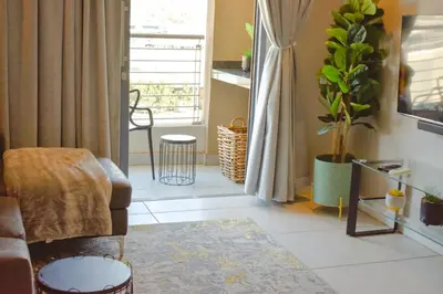 a living room with a chair and a plant at Menlyn Apartment - Red Velvet in Pretoria