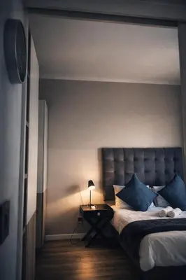 a bedroom with a bed and a table with a lamp at Menlyn Apartment - Red Velvet in Pretoria