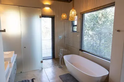 a bathroom with a large tub and a window at Kruger River Lodge in Hoedspruit