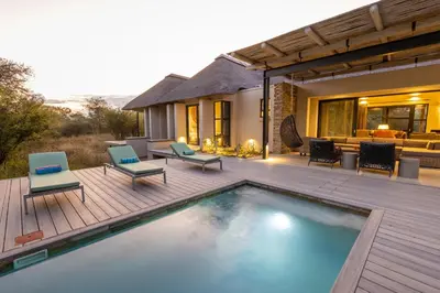 a backyard with a swimming pool and a house at Kruger River Lodge in Hoedspruit