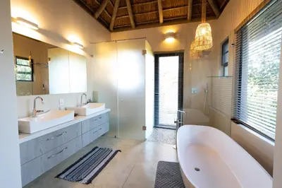 a bathroom with two sinks and a bath tub at Kruger River Lodge in Hoedspruit