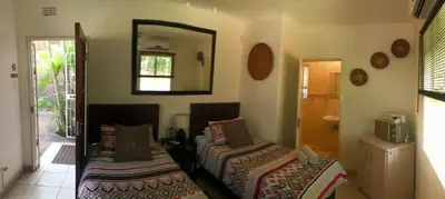 a bedroom with two beds and a mirror at Danamara Garden Studios in Phalaborwa