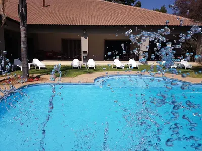a model of a swimming pool with white chairs at Summerset Place Country House in Bela-Bela