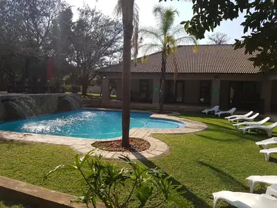 a pool with chairs and a palm tree in a yard at Summerset Place Country House in Bela-Bela