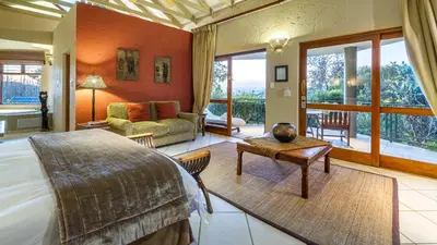 a bedroom with a bed and a living room at Jörn's Gästehaus in Nelspruit