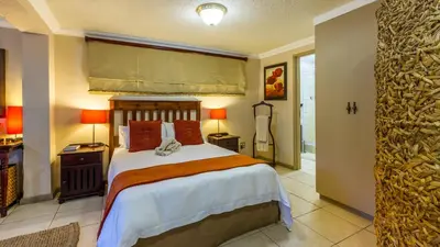 a bedroom with a large bed and a bathroom at Jörn's Gästehaus in Nelspruit