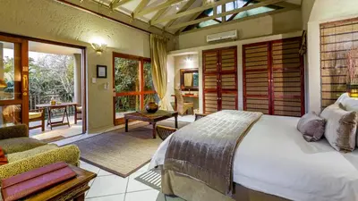 a bedroom with a bed and a living room at Jörn's Gästehaus in Nelspruit
