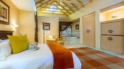 a bedroom with a large bed and a couch at Jörn's Gästehaus in Nelspruit