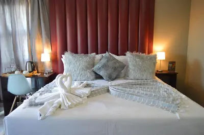 a bedroom with a white bed with a red headboard at Clifford's Rufaro Hotel, Conference & Spa in Burgersfort